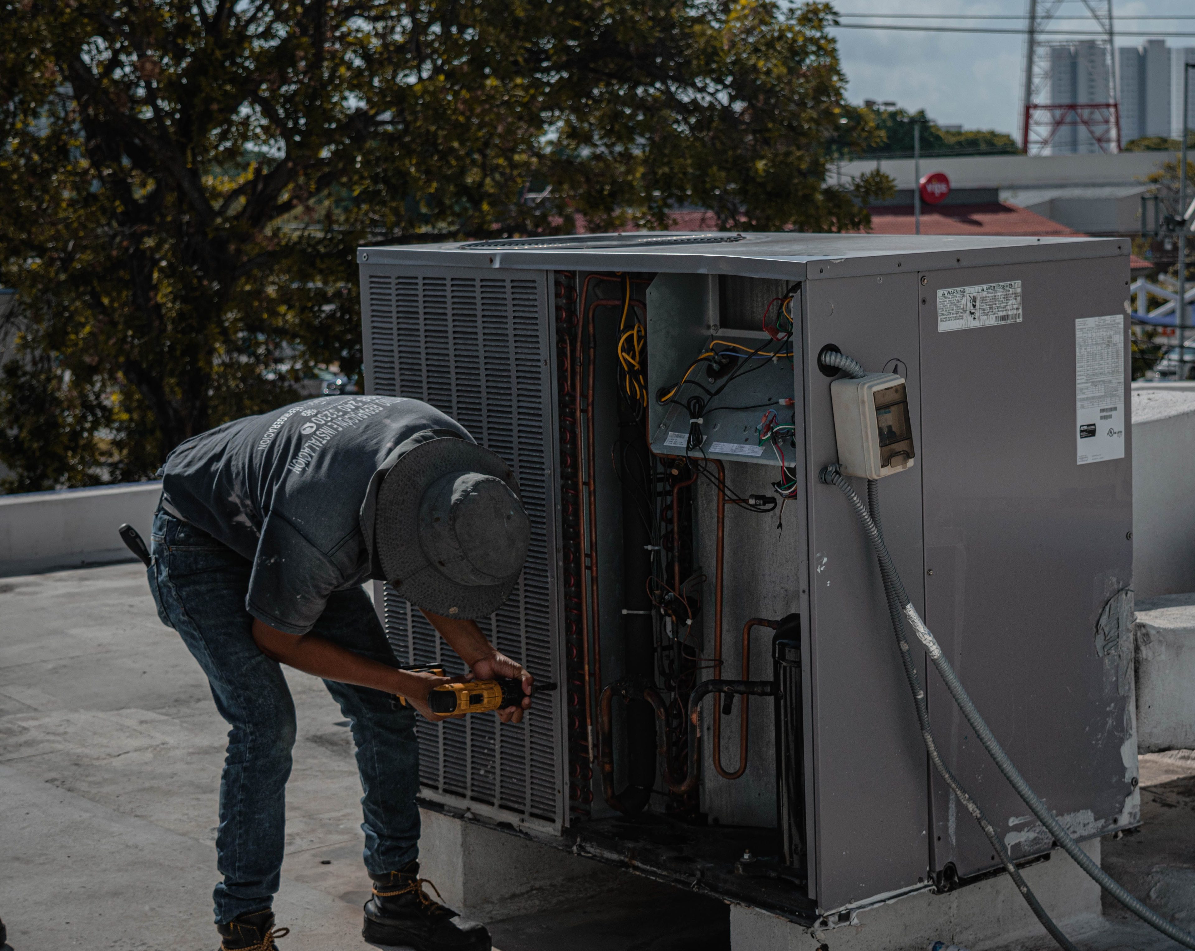 A technician drilling into the casing of an air conditioning unit